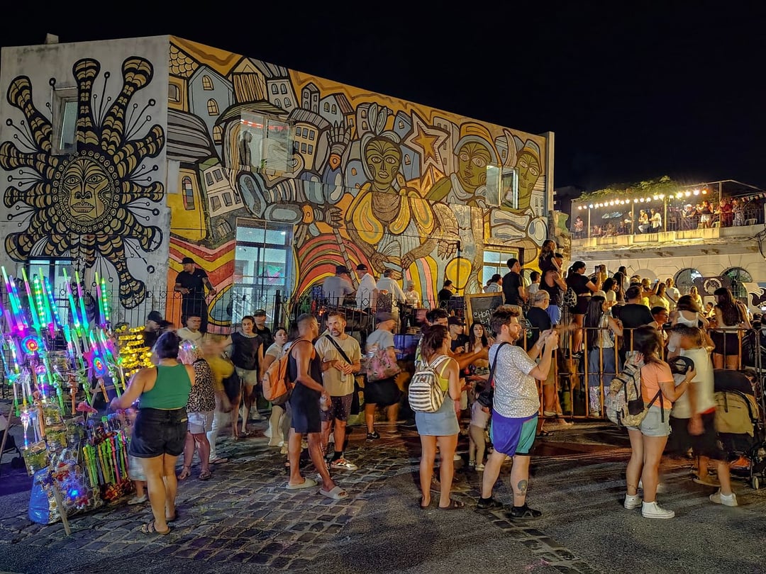 Público esperando el Desfile de Llamadas de noche, frente a un mural de temática afrouruguaya en el Barrio Sur