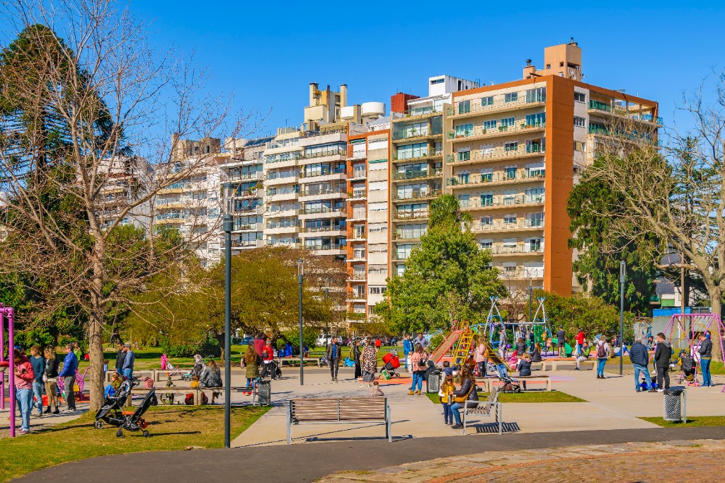 Parque Villa Biarritz con juegos, palmeras y edificios de apartamentos